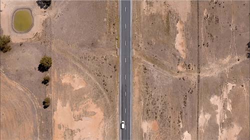 Overheard shot of van driving on a desert road